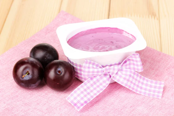Yoghurt met bosbessen en pruimen op houten tafel — Stockfoto