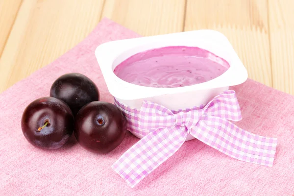 Yogur con arándanos y ciruelas sobre mesa de madera — Foto de Stock