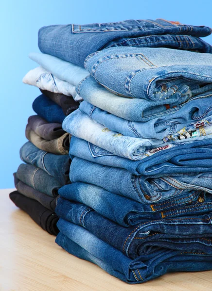 Beaucoup de jeans empilés dans un tas sur fond bleu — Photo