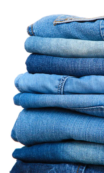 Molti jeans impilati in un mucchio isolato su bianco — Foto Stock