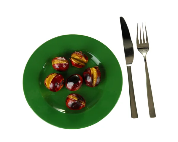 Roasted chestnuts in the green plate with fork and knife isolated on white — Stock Photo, Image