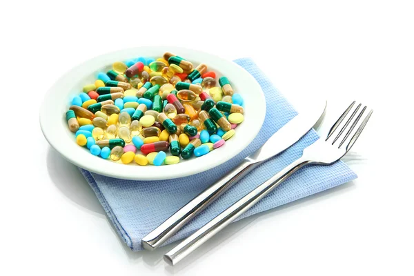 Capsule e pillole colorate su piastra con forchetta e coltello, isolate su bianco — Foto Stock