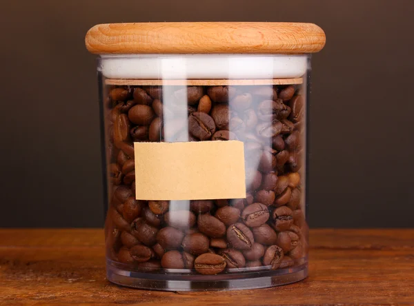 Kaffeebohnen im Glas auf dem Tisch auf braunem Hintergrund — Stockfoto