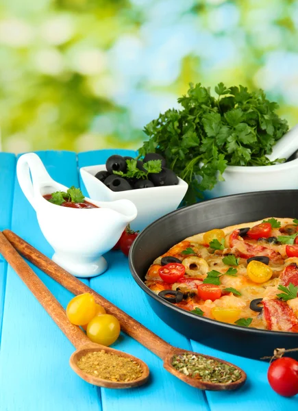 Composición colorida de deliciosa pizza, verduras y especias en madera azul —  Fotos de Stock