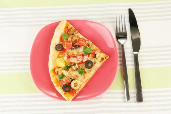 Prato com uma fatia de pizza deliciosa na toalha de mesa close-up — Fotografia de Stock