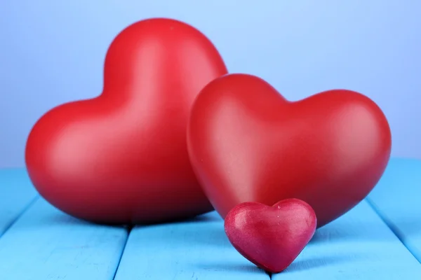 Decorative red hearts on blue wooden table on blue background — Stock Photo, Image