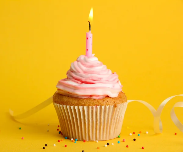 Вкусный день рождения кекс со свечой, на желтом фоне — стоковое фото