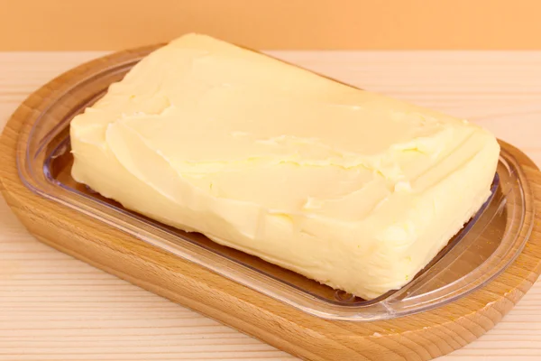 Beurre sur support en bois sur table en bois sur fond beige — Photo