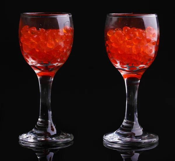 Caviar vermelho em óculos isolados em preto — Fotografia de Stock