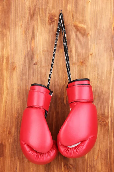 Gants de boxe rouge suspendus sur fond en bois — Photo