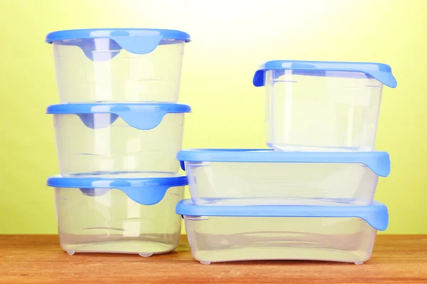 Recipientes de plástico para alimentos em mesa de madeira em fundo verde — Fotografia de Stock