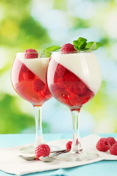 Fruchtgelee in Gläsern, Beeren und Minze auf Tisch auf grünem Hintergrund — Stockfoto