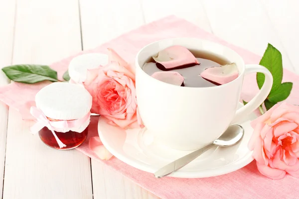 Tazza di tè con rose e marmellata sul tavolo di legno bianco — Foto Stock