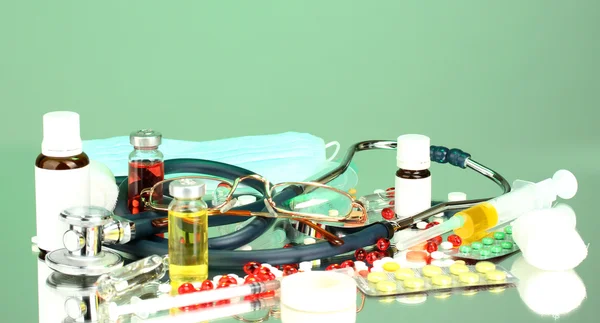 Medicamentos e um estetoscópio em um fundo verde close-up — Fotografia de Stock