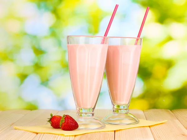 Strawberry milk shakes on wooden table on bright background — Stock Photo, Image