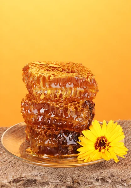 Favo de mel na mesa de madeira no fundo laranja — Fotografia de Stock