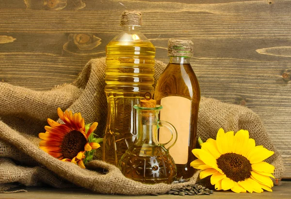 Aceite en botellas, girasoles y semillas, sobre fondo de madera —  Fotos de Stock