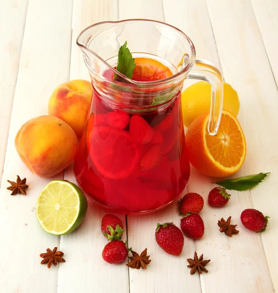 Sangria em jarra com frutas, sobre mesa de madeira branca — Fotografia de Stock