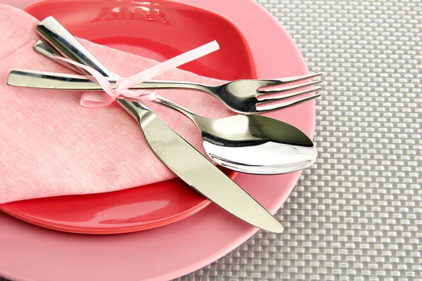 Platos vacíos rosados con tenedor, cuchara y cuchillo sobre un mantel gris —  Fotos de Stock