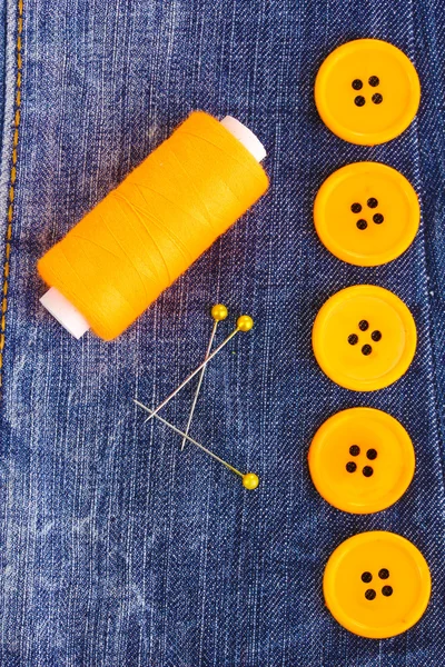 Colorful sewing buttons with thread on jeans closeup — Stock Photo, Image