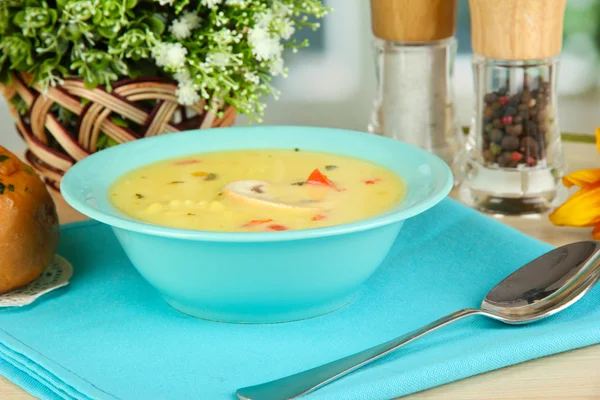 Ароматный суп в голубой тарелке на столе на фоне окна крупным планом — стоковое фото