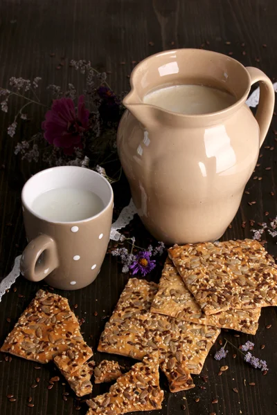 Pitcher and cup of milk with cookies on wooden table close-up — Stock Photo, Image