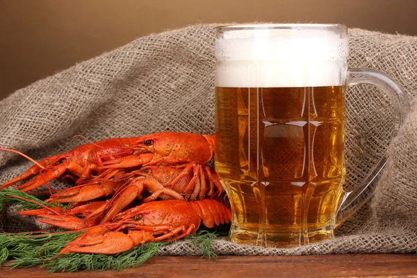 Sabroso cangrejos de río hervidos y cerveza en la mesa sobre fondo marrón —  Fotos de Stock