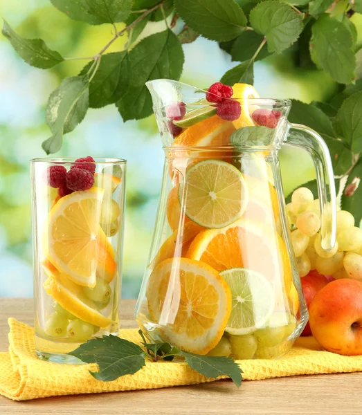 Jar and glass with citrus fruits and raspberries, on green background — Stock Photo, Image