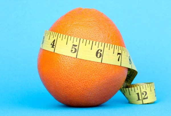 Orange with measuring tape on blue background — Stock Photo, Image