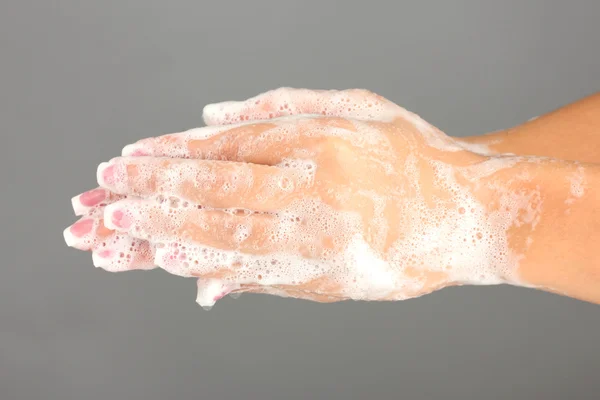 Mani di donna in sapone, su sfondo grigio primo piano — Foto Stock