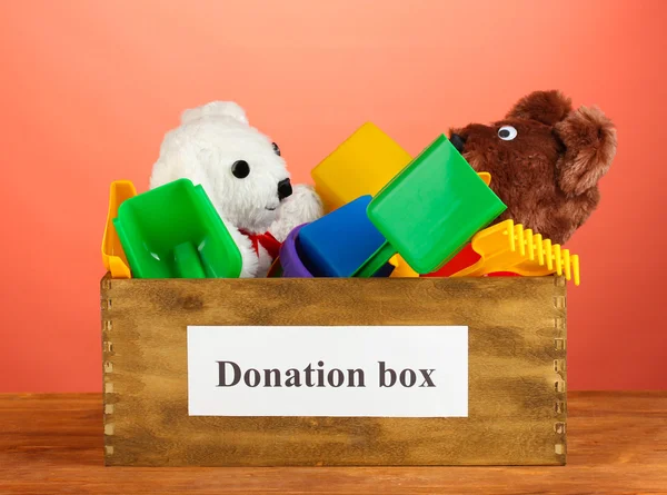Donation box with children toys on red background close-up — Stock Photo, Image