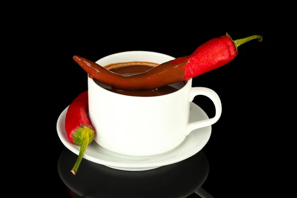 White cup with hot chocolate and chili pepper isolated on black Stock Image