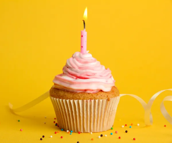 Tasty birthday cupcake with candle, on yellow background Stock Photo