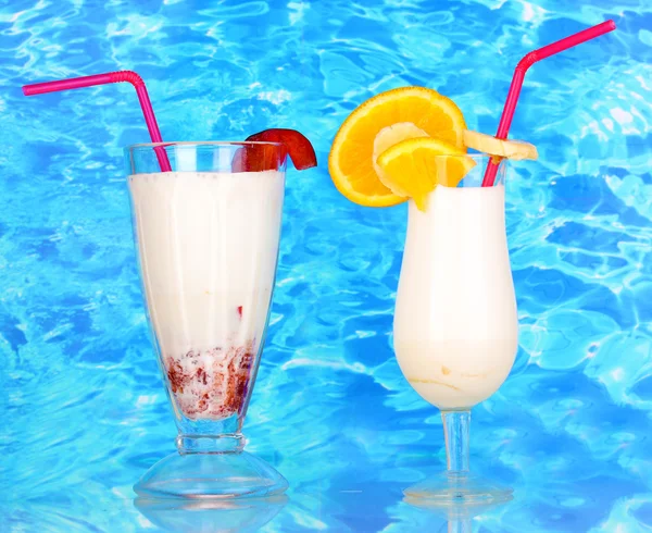 Delicious milk shake with fruit on table on blue sea background — Stock Photo, Image