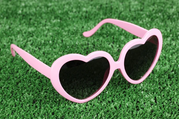 Lunettes de soleil roses en forme de coeur sur herbe verte — Photo