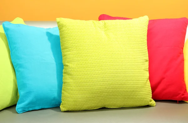 Colorful pillows on couch on yellow background — Stock Photo, Image