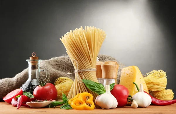 Паста-спагетти, овощи и специи, на деревянном столе, на сером фоне — стоковое фото