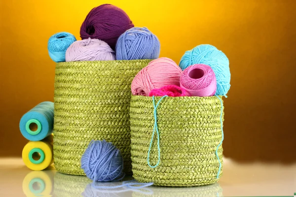 Barevné příze pro pletení v zelené koše na oranžovém pozadí — Stock fotografie