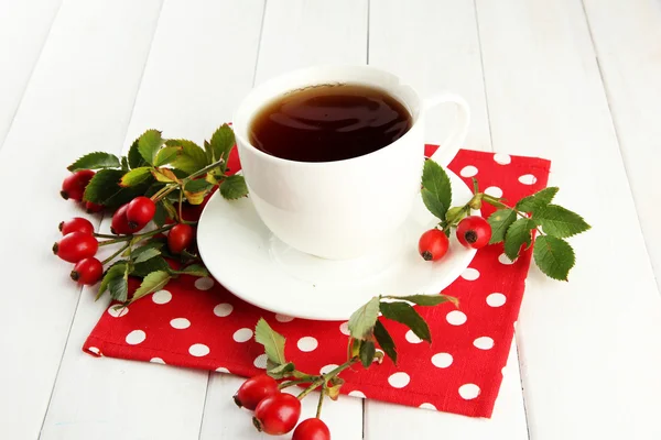 Tazza di tè con rose dell'anca, sul tavolo di legno — Foto Stock