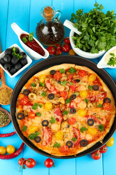 Composición colorida de deliciosa pizza, verduras y especias en madera azul — Foto de Stock