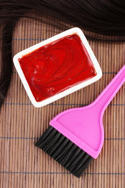 Tinte para el cabello en el tazón y el cepillo para la coloración del cabello en la estera de bambú marrón, primer plano — Foto de Stock