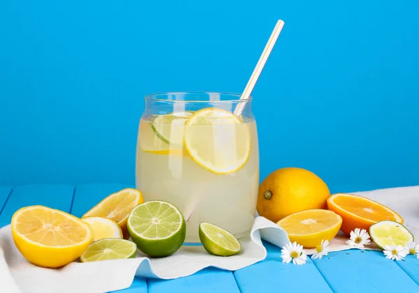 Citrus limonade in glas bank van citrus rond op houten tafel blauwe achterop — Stockfoto
