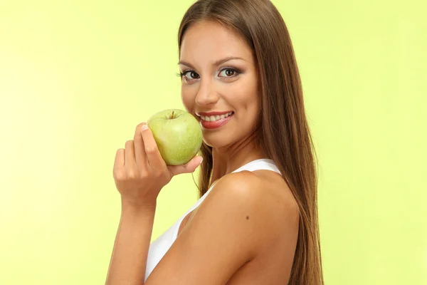 Beautiful young woman with green apple, on green background — Stock Photo, Image