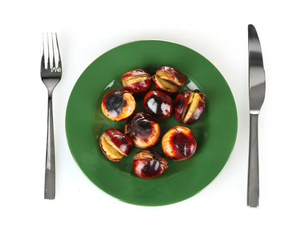 Roasted chestnuts in the green plate with fork and knife isolated on white Stock Image