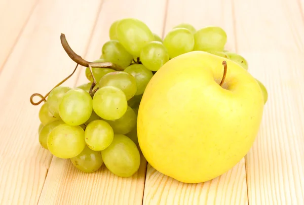 Rijpe zoete druiven en apple op houten achtergrond — Stockfoto
