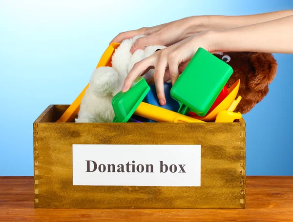 Donatie box met kinderen speelgoed op blauwe achtergrond close-up — Stockfoto