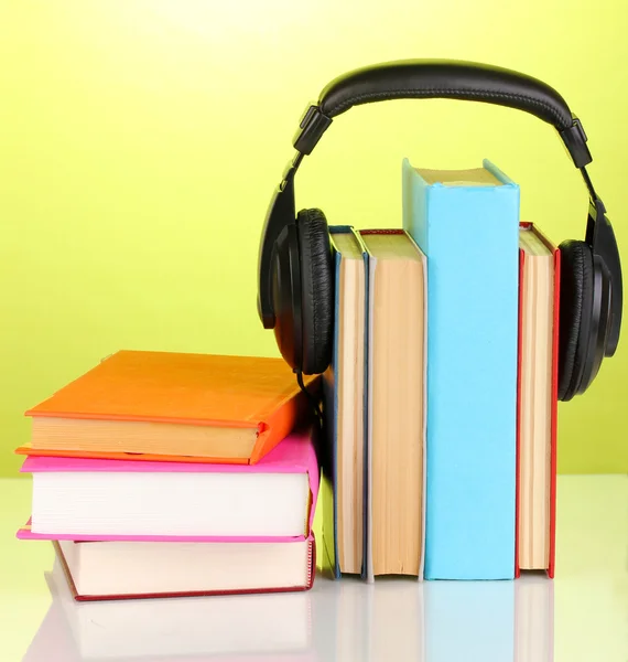 Auriculares en libros sobre fondo verde —  Fotos de Stock