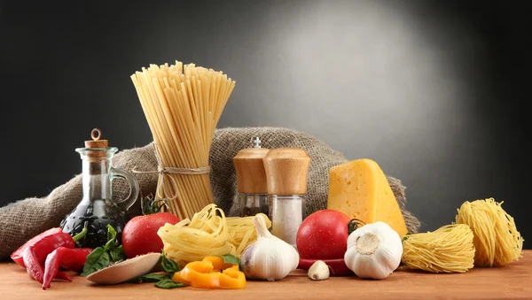 Nudelspaghetti, Gemüse und Gewürze, auf Holztisch, auf grauem Hintergrund — Stockfoto