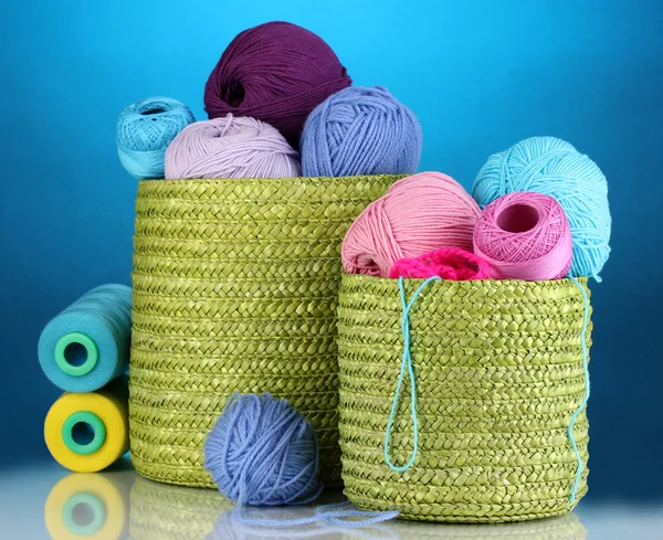 Colorful yarn for knitting in green basket on blue background — Stock Photo, Image