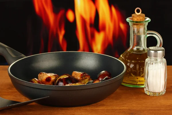 Castagne arrosto in padella e decanter con olio, sale e pepe su legno — Foto Stock